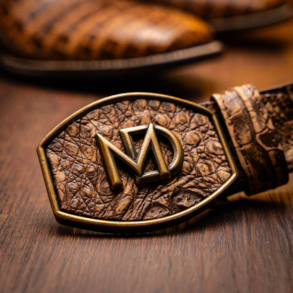 A pair of Tucson Stone Brown cowboy boots by Marco Di Milano, featuring brown leather with a reptile texture and square toe; one boot stands upright, the other displays its sole labeled with the brand.