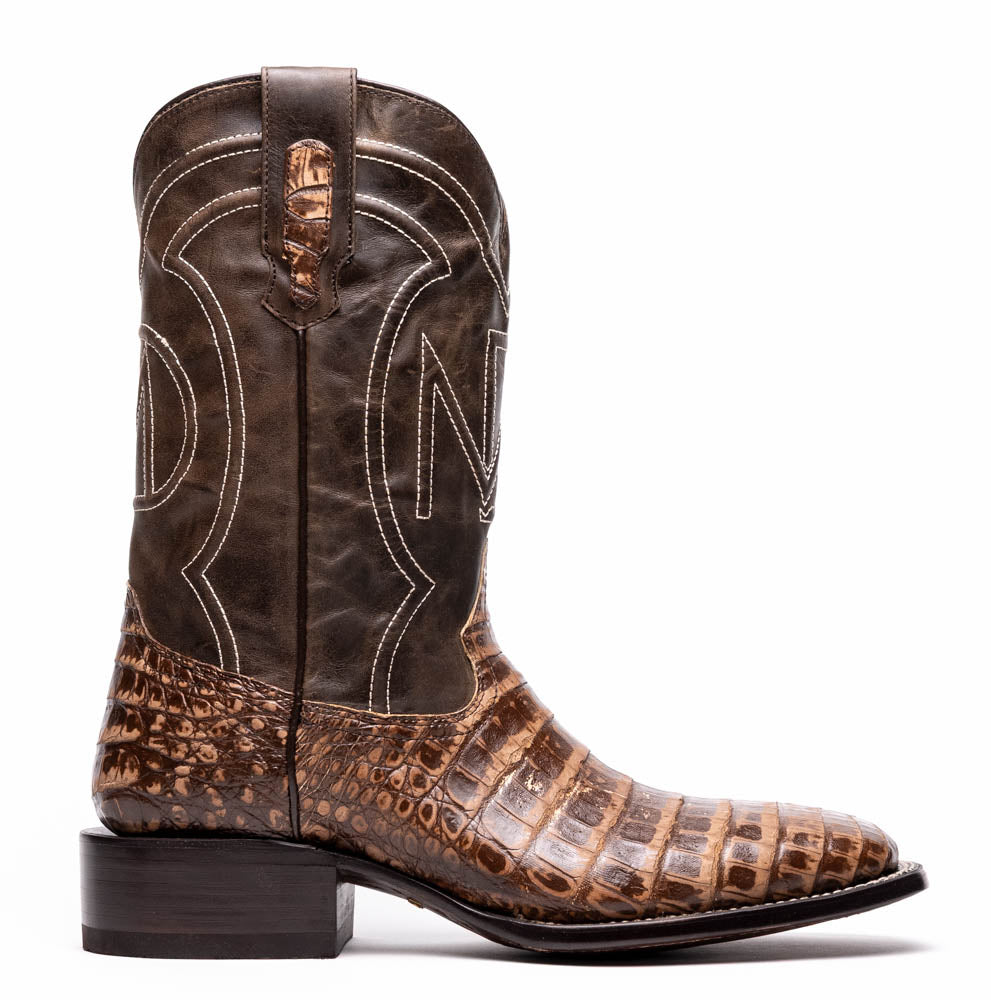 A pair of Tucson Stone Brown cowboy boots by Marco Di Milano, featuring brown leather with a reptile texture and square toe; one boot stands upright, the other displays its sole labeled with the brand.
