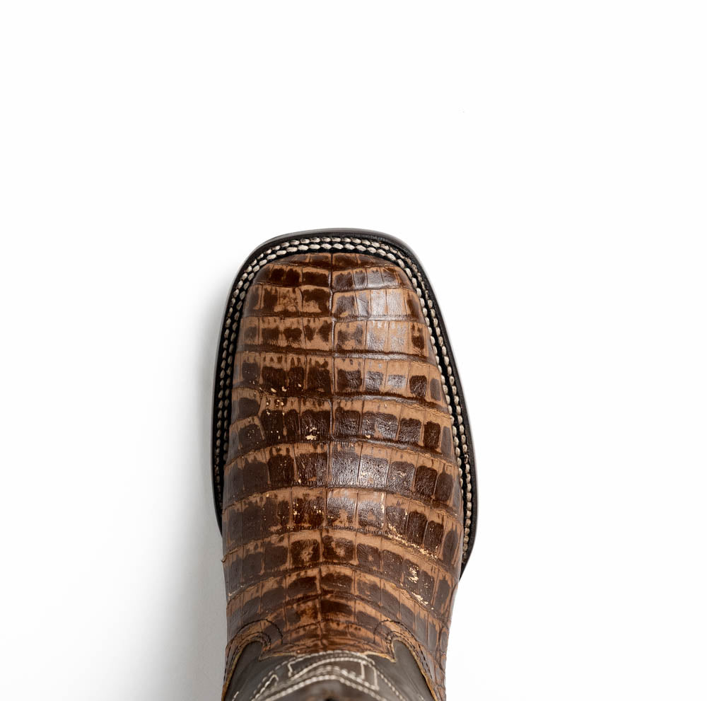 A pair of Tucson Stone Brown cowboy boots by Marco Di Milano, featuring brown leather with a reptile texture and square toe; one boot stands upright, the other displays its sole labeled with the brand.