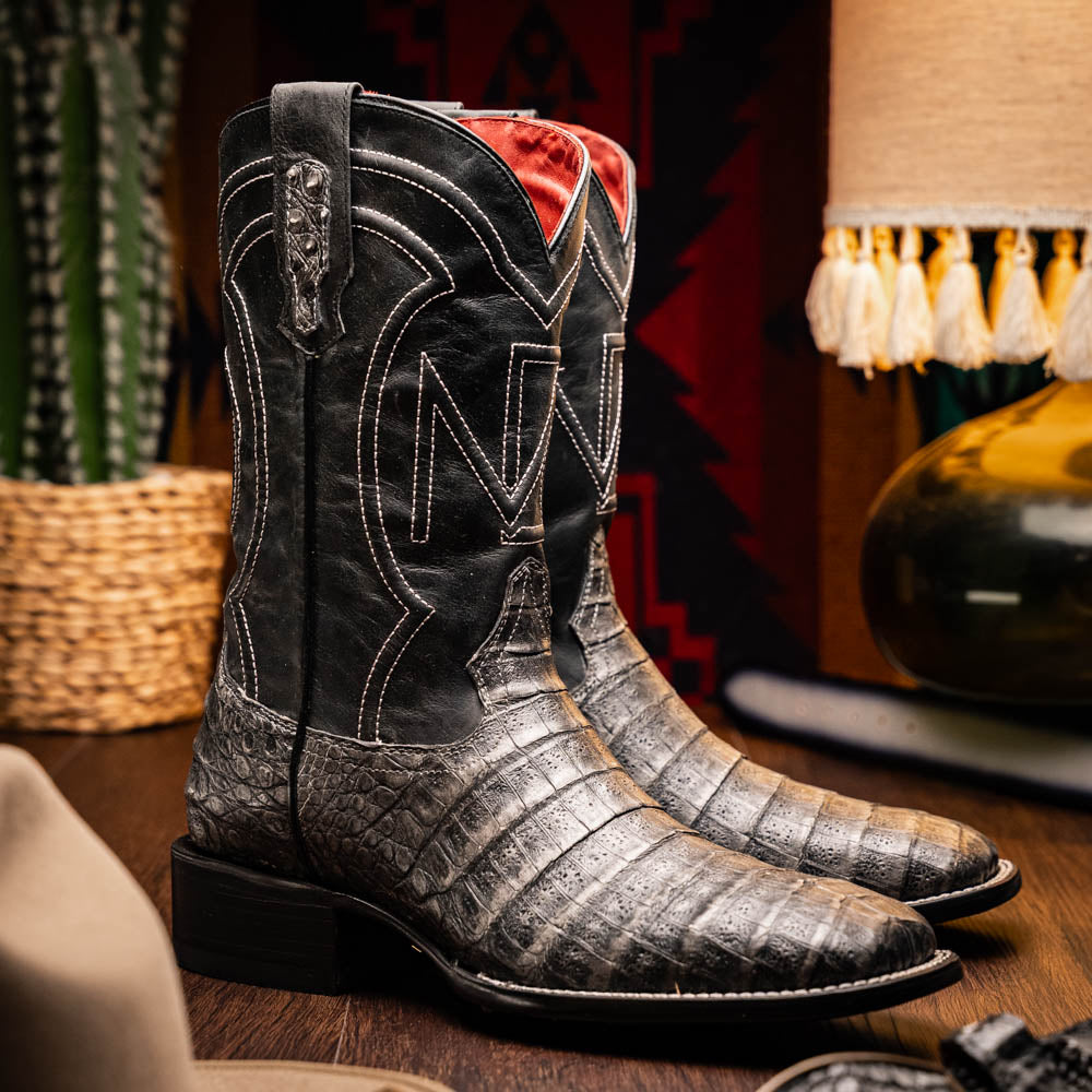 A pair of Tucson Stone Gray cowboy boots by Marco Di Milano with exotic textured leather, detailed white stitching, red inner lining, and the brand logo on the sole.