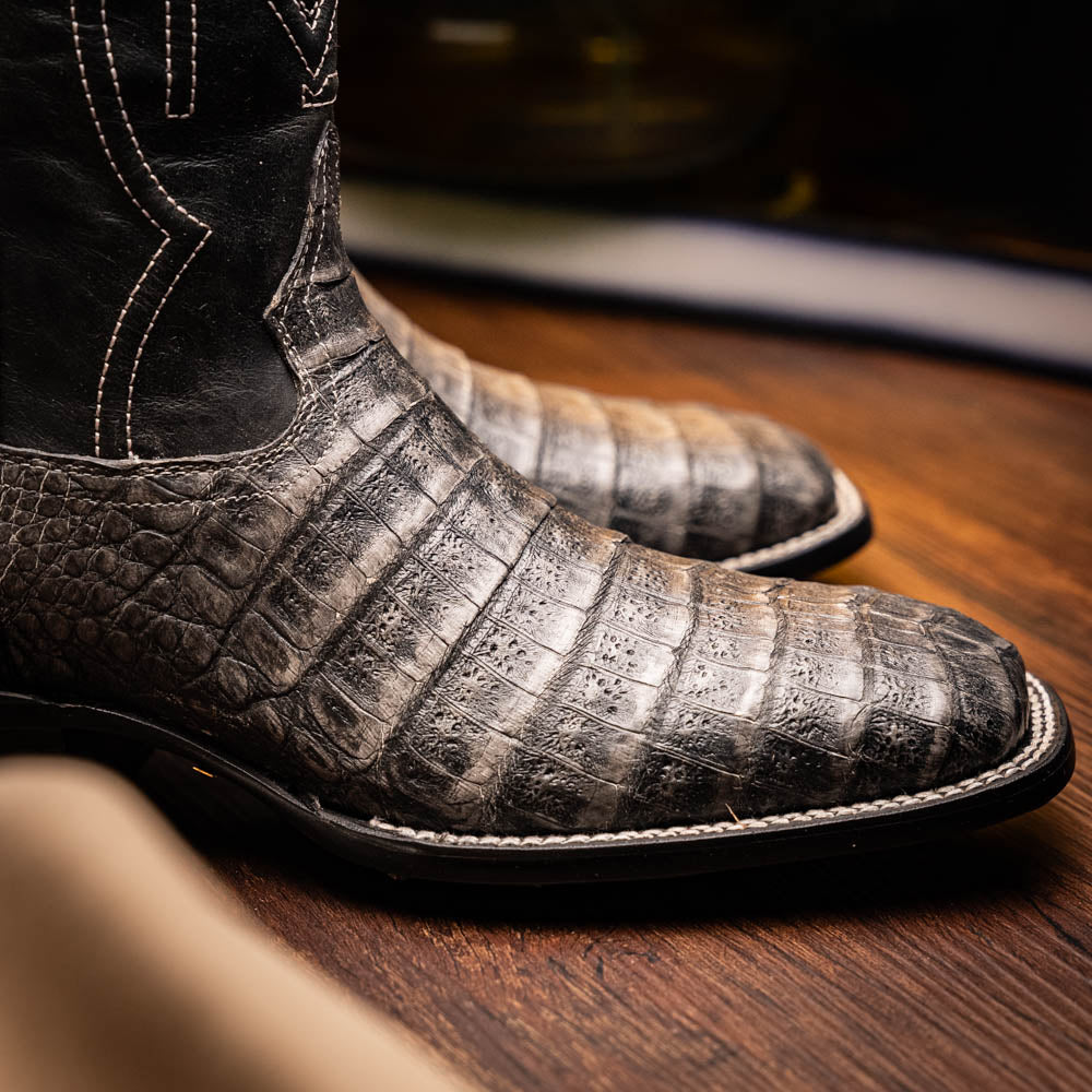 A pair of Tucson Stone Gray cowboy boots by Marco Di Milano with exotic textured leather, detailed white stitching, red inner lining, and the brand logo on the sole.