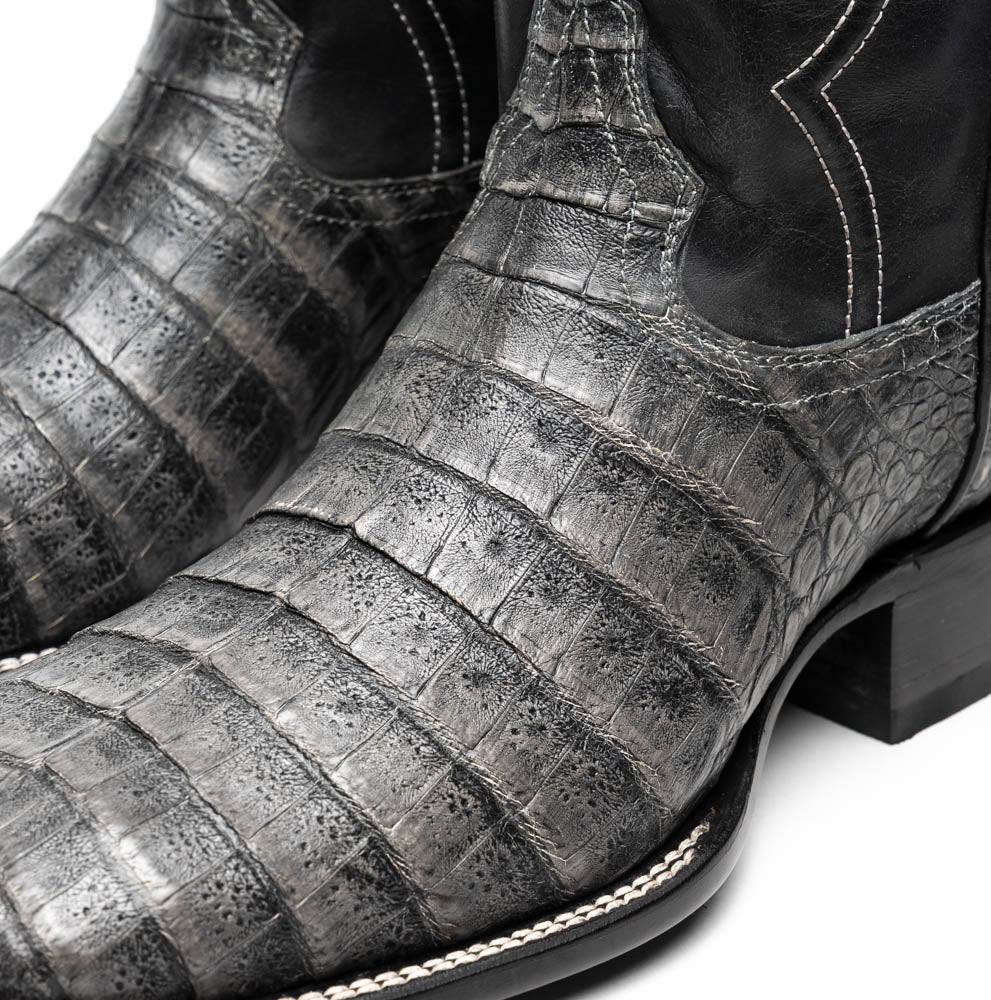 A pair of Tucson Stone Gray cowboy boots by Marco Di Milano with exotic textured leather, detailed white stitching, red inner lining, and the brand logo on the sole.