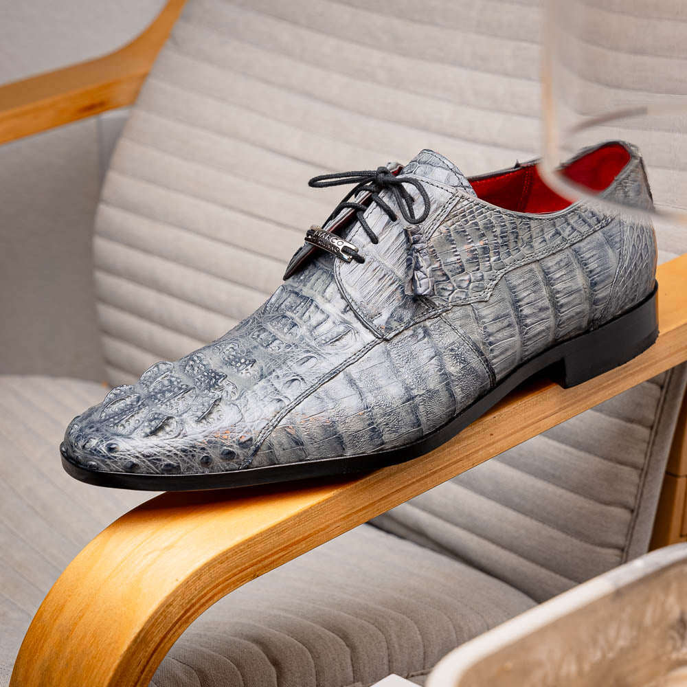 The Tulum Gray by Marco Di Milano is a luxury men’s dress shoe in genuine caiman crocodile leather, featuring black laces and a metal ornament, shown with one shoe on its side to display the branded leather sole.