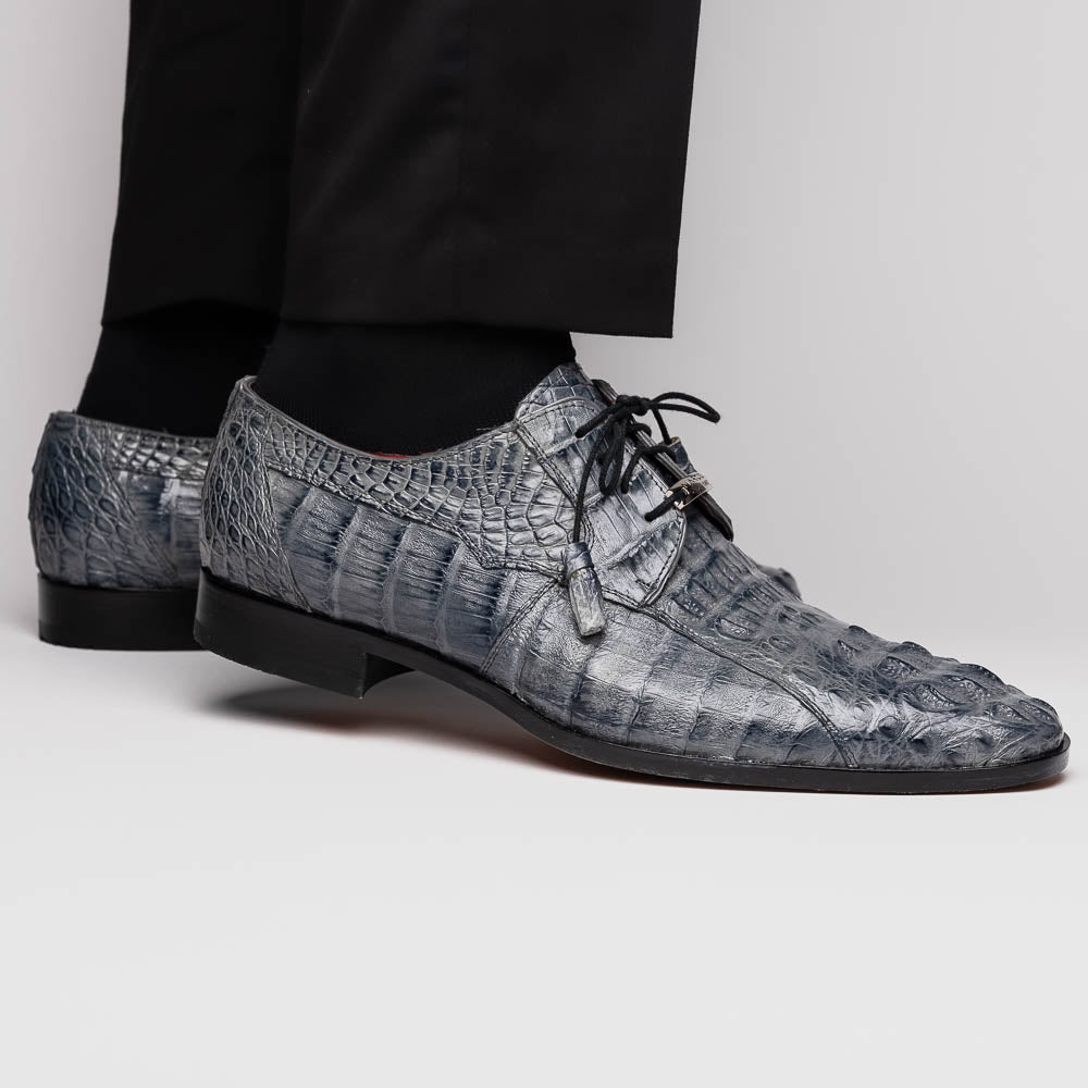 The Tulum Gray by Marco Di Milano is a luxury men’s dress shoe in genuine caiman crocodile leather, featuring black laces and a metal ornament, shown with one shoe on its side to display the branded leather sole.