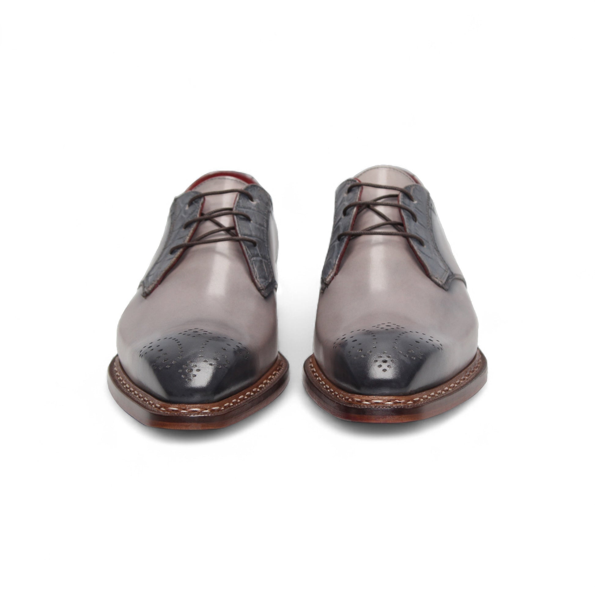 The Fennix Tyler Light Grey by Fennix of Italy is a gray and light gray dress shoe with brogue detailing, red inner lining, and a leather sole, expertly crafted in Italy and displayed in a side profile view.