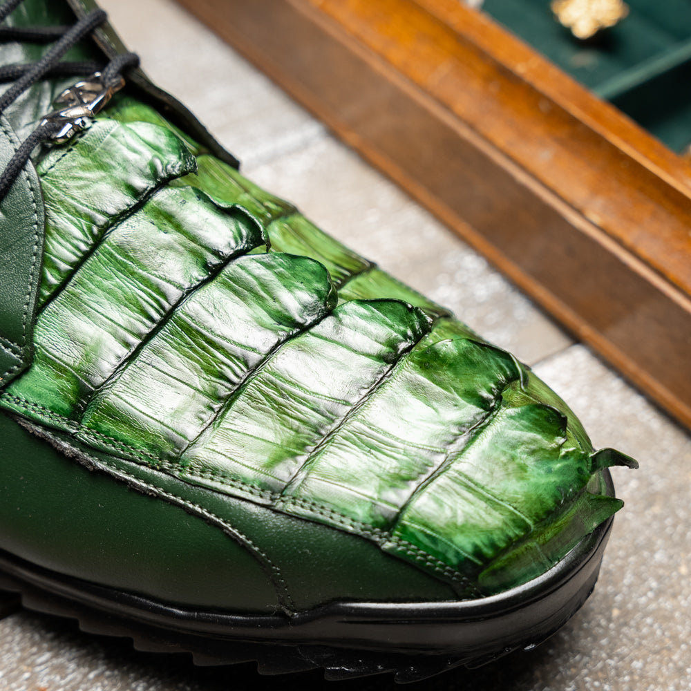Introducing the Udine Green by Marco Di Milano: luxury men’s shoes in dark green, crafted from exotic hornback caiman leather. These dress shoes showcase a textured, scale-like front design, black laces, and decorative metal initials on the tongue—all displayed against a white background.
