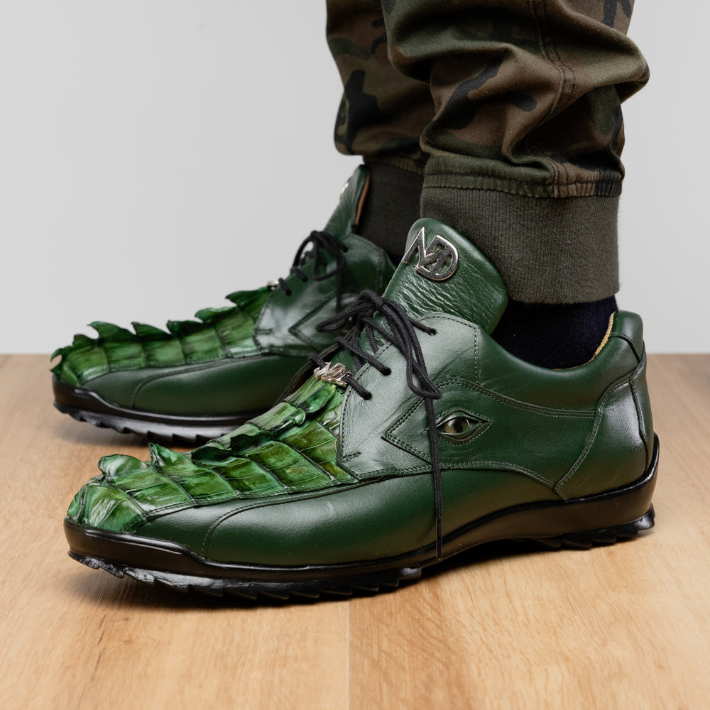 Introducing the Udine Green by Marco Di Milano: luxury men’s shoes in dark green, crafted from exotic hornback caiman leather. These dress shoes showcase a textured, scale-like front design, black laces, and decorative metal initials on the tongue—all displayed against a white background.
