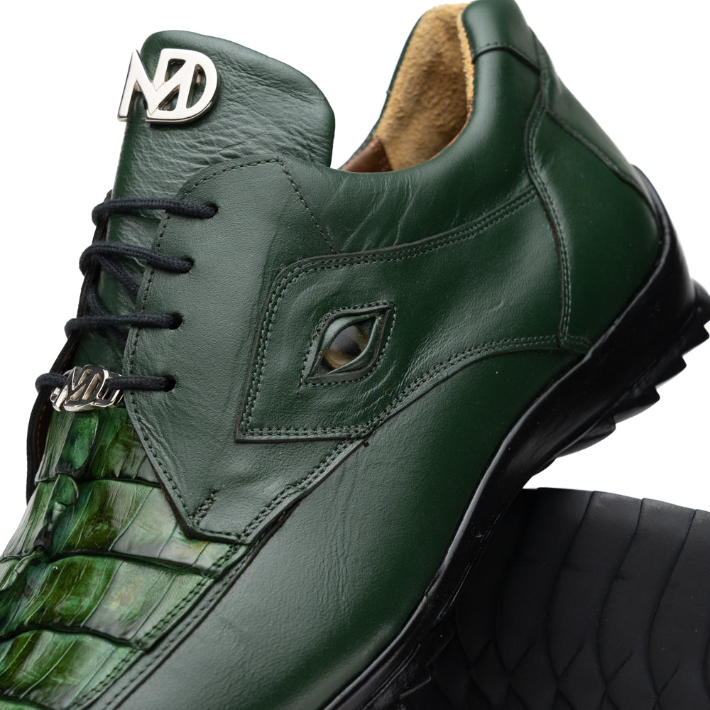 Introducing the Udine Green by Marco Di Milano: luxury men’s shoes in dark green, crafted from exotic hornback caiman leather. These dress shoes showcase a textured, scale-like front design, black laces, and decorative metal initials on the tongue—all displayed against a white background.