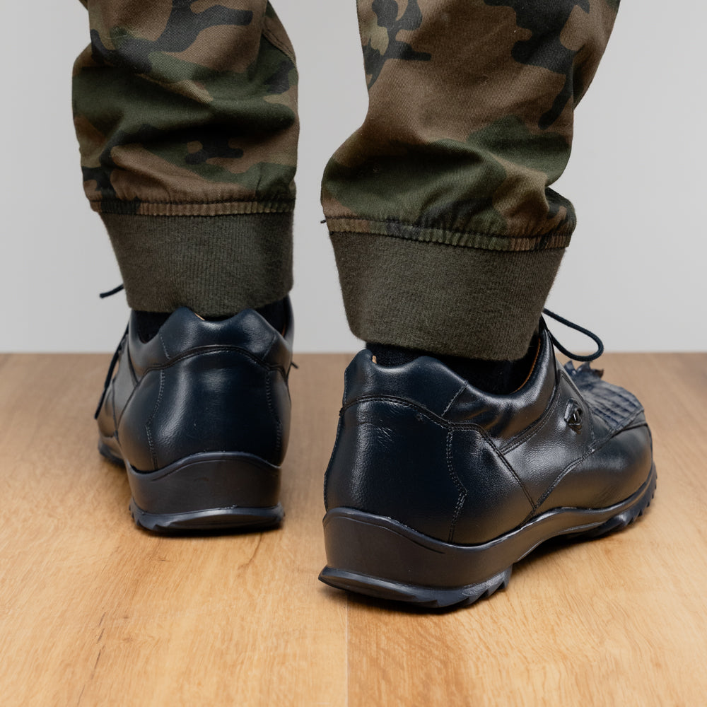 Introducing the Udine Navy by Marco Di Milano—a pair of luxury men’s sneakers crafted from exotic navy blue leather with textured uppers and durable rubber soles. One shoe stands upright while the other rests on its side, showcasing their distinctive style and impeccable craftsmanship.