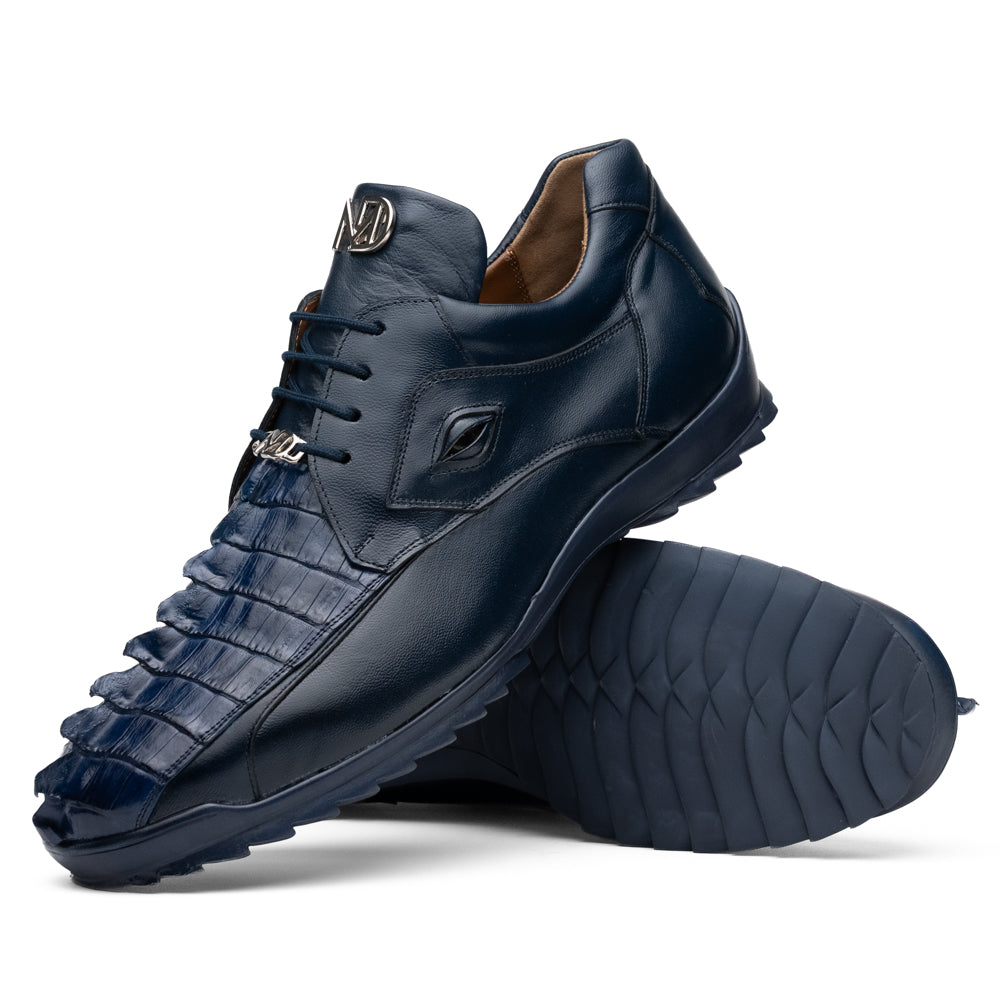 Introducing the Udine Navy by Marco Di Milano—a pair of luxury men’s sneakers crafted from exotic navy blue leather with textured uppers and durable rubber soles. One shoe stands upright while the other rests on its side, showcasing their distinctive style and impeccable craftsmanship.