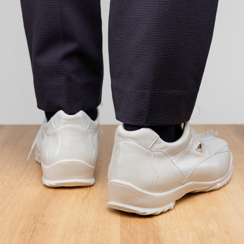 The Udine White by Marco Di Milano is a pair of luxury men’s sneakers crafted from white hornback caiman leather with a distinctive crocodile pattern, featuring a gold logo on the tongue and textured rubber soles. Displayed with one shoe upright and the other leaning against it, this footwear exudes sophistication and unique style.