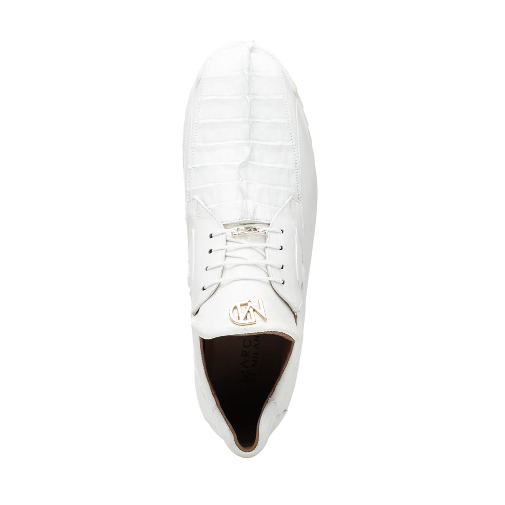 The Udine White by Marco Di Milano is a pair of luxury men’s sneakers crafted from white hornback caiman leather with a distinctive crocodile pattern, featuring a gold logo on the tongue and textured rubber soles. Displayed with one shoe upright and the other leaning against it, this footwear exudes sophistication and unique style.