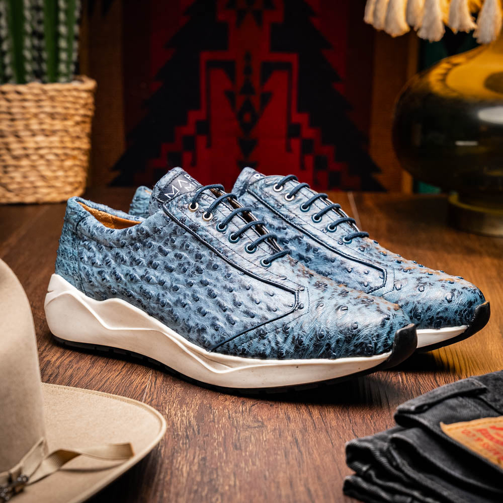 A pair of Marco Di Milano Varenna Blue Jeans sneakers—blue handcrafted leather with white soles and black laces—one upright, the other propped to display its sole.