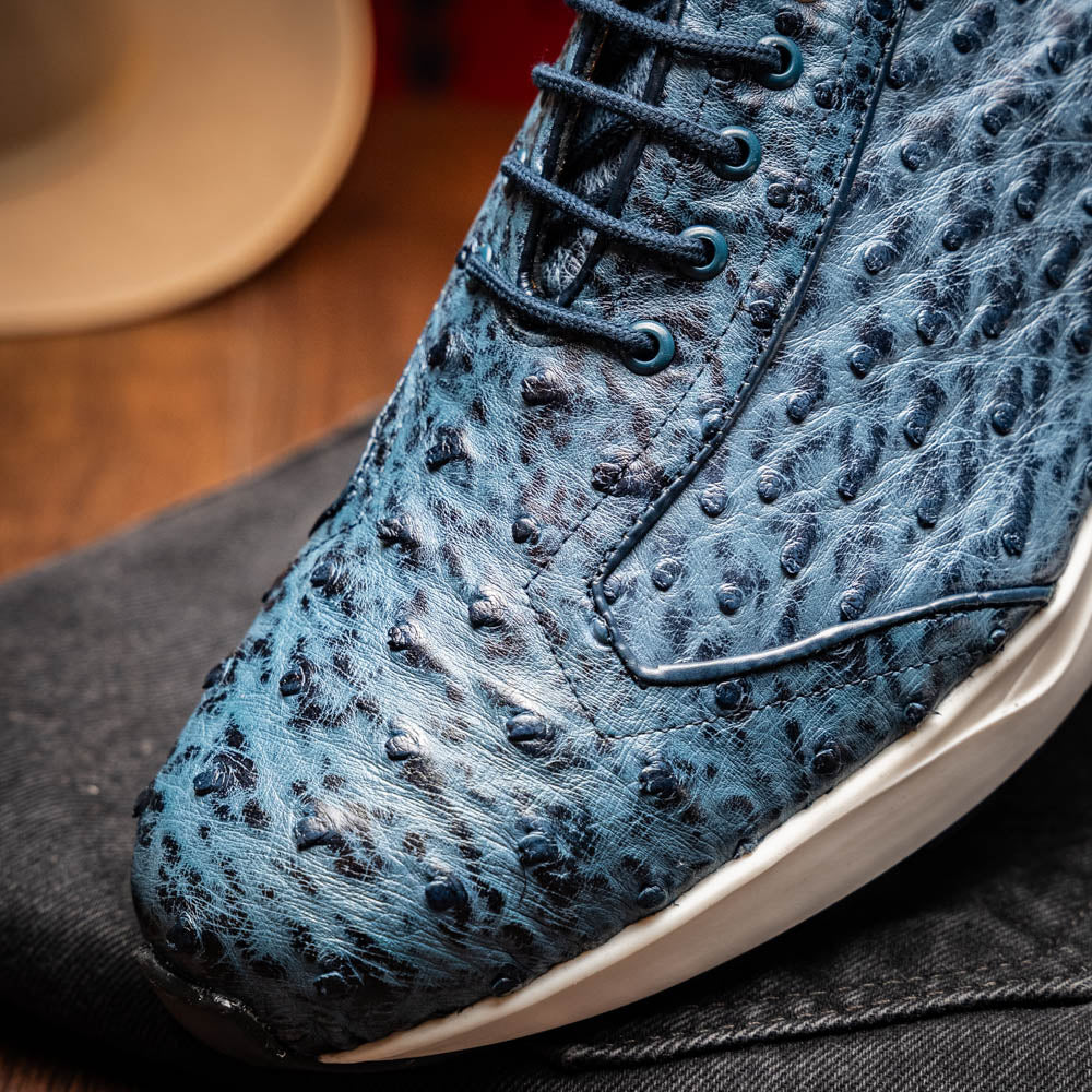 A pair of Marco Di Milano Varenna Blue Jeans sneakers—blue handcrafted leather with white soles and black laces—one upright, the other propped to display its sole.