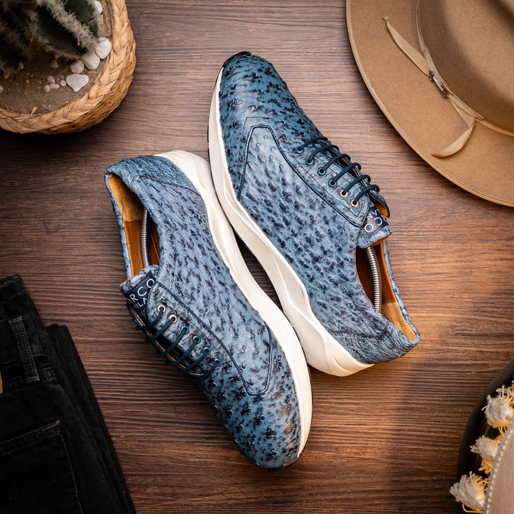 A pair of Marco Di Milano Varenna Blue Jeans sneakers—blue handcrafted leather with white soles and black laces—one upright, the other propped to display its sole.