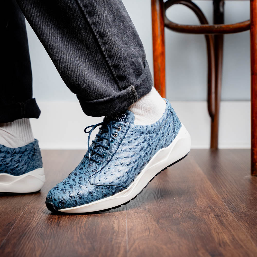 A pair of Marco Di Milano Varenna Blue Jeans sneakers—blue handcrafted leather with white soles and black laces—one upright, the other propped to display its sole.