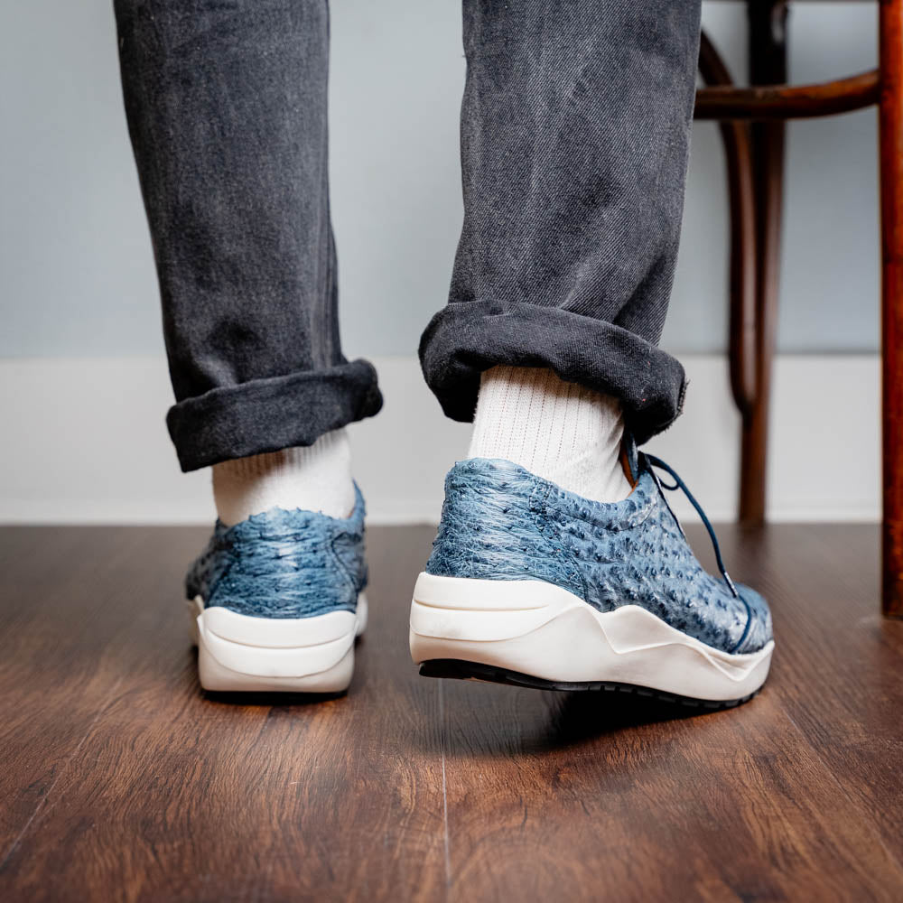 A pair of Marco Di Milano Varenna Blue Jeans sneakers—blue handcrafted leather with white soles and black laces—one upright, the other propped to display its sole.