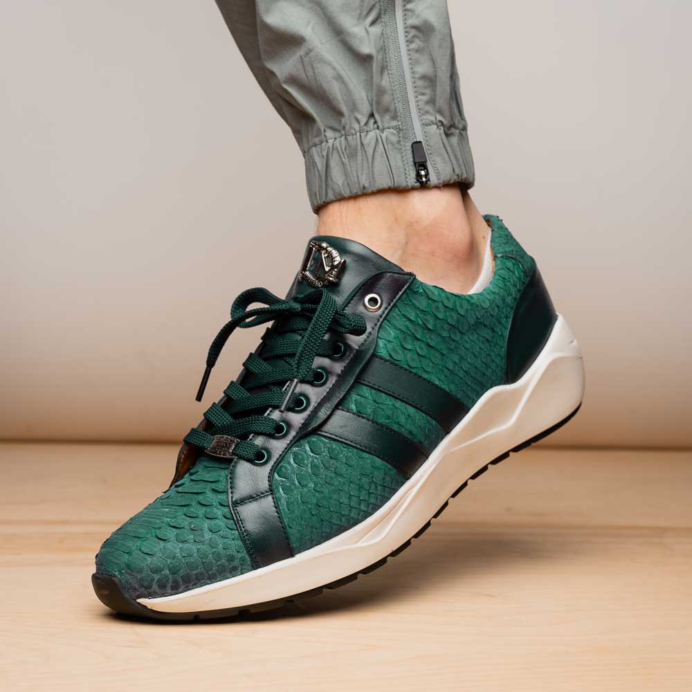 The Marco Di Milano Verona Green sneakers are luxury shoes with scale-like patterns, dark green accents, and white soles. One shoe is upright while the other lies on its side.