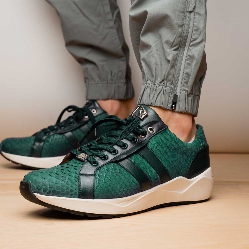 The Marco Di Milano Verona Green sneakers are luxury shoes with scale-like patterns, dark green accents, and white soles. One shoe is upright while the other lies on its side.