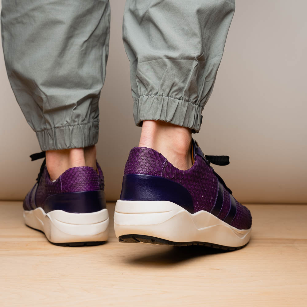 The Verona Purple by Marco Di Milano are hand-painted python sneakers with a textured scale pattern, black laces, and white soles—ideal for elevating any men's sneaker collection. One shoe stands while the other lies on its side.