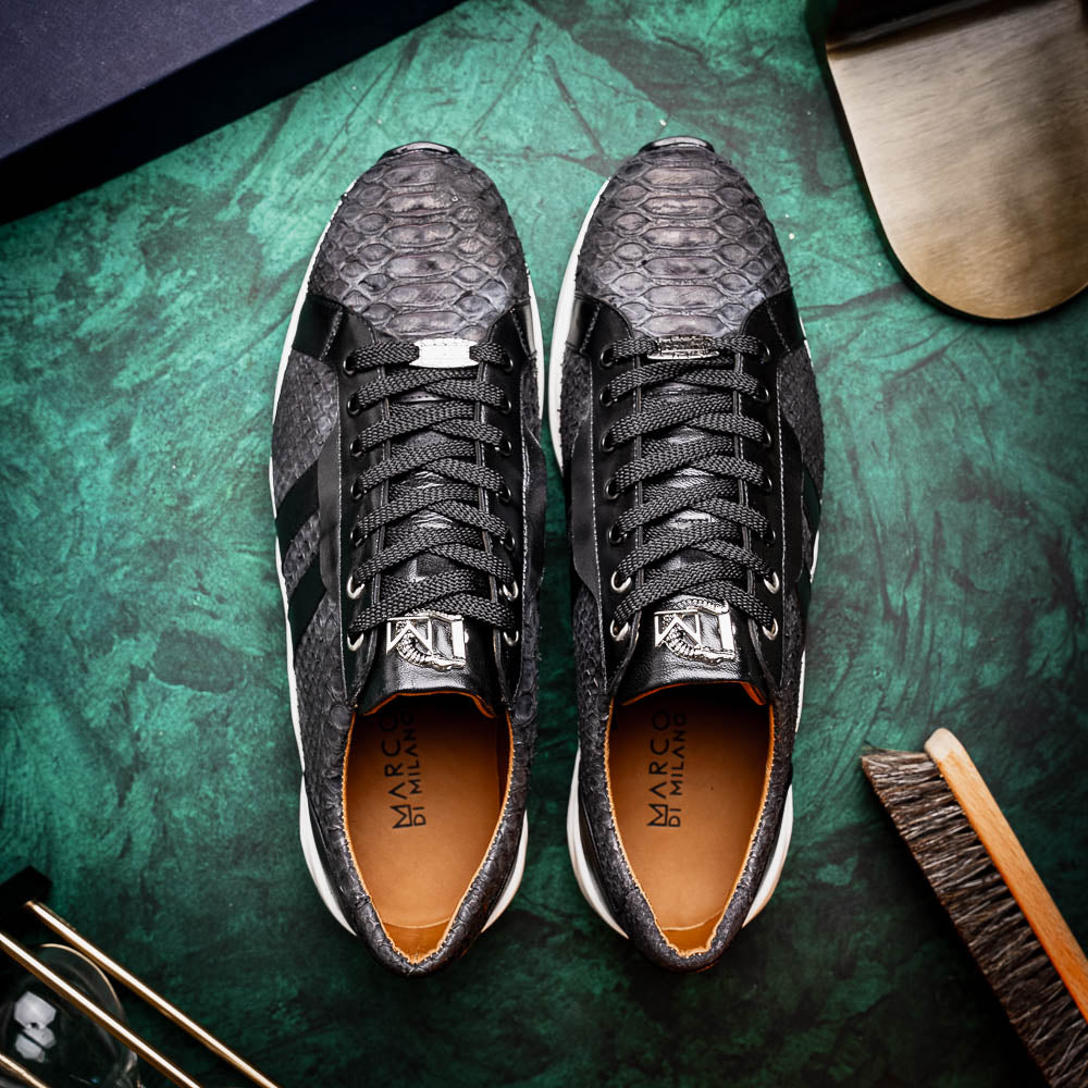 The Verona Black sneakers by Marco Di Milano feature a black textured design, white soles, black laces, and dual black side stripes; one shoe stands upright, while the other lies on its side displaying the sole.
