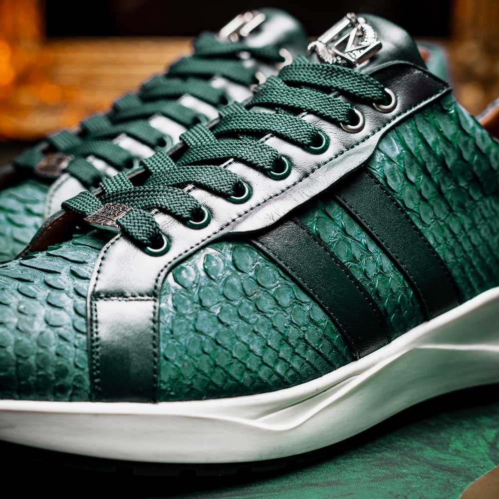 The Marco Di Milano Verona Green sneakers are luxury shoes with scale-like patterns, dark green accents, and white soles. One shoe is upright while the other lies on its side.