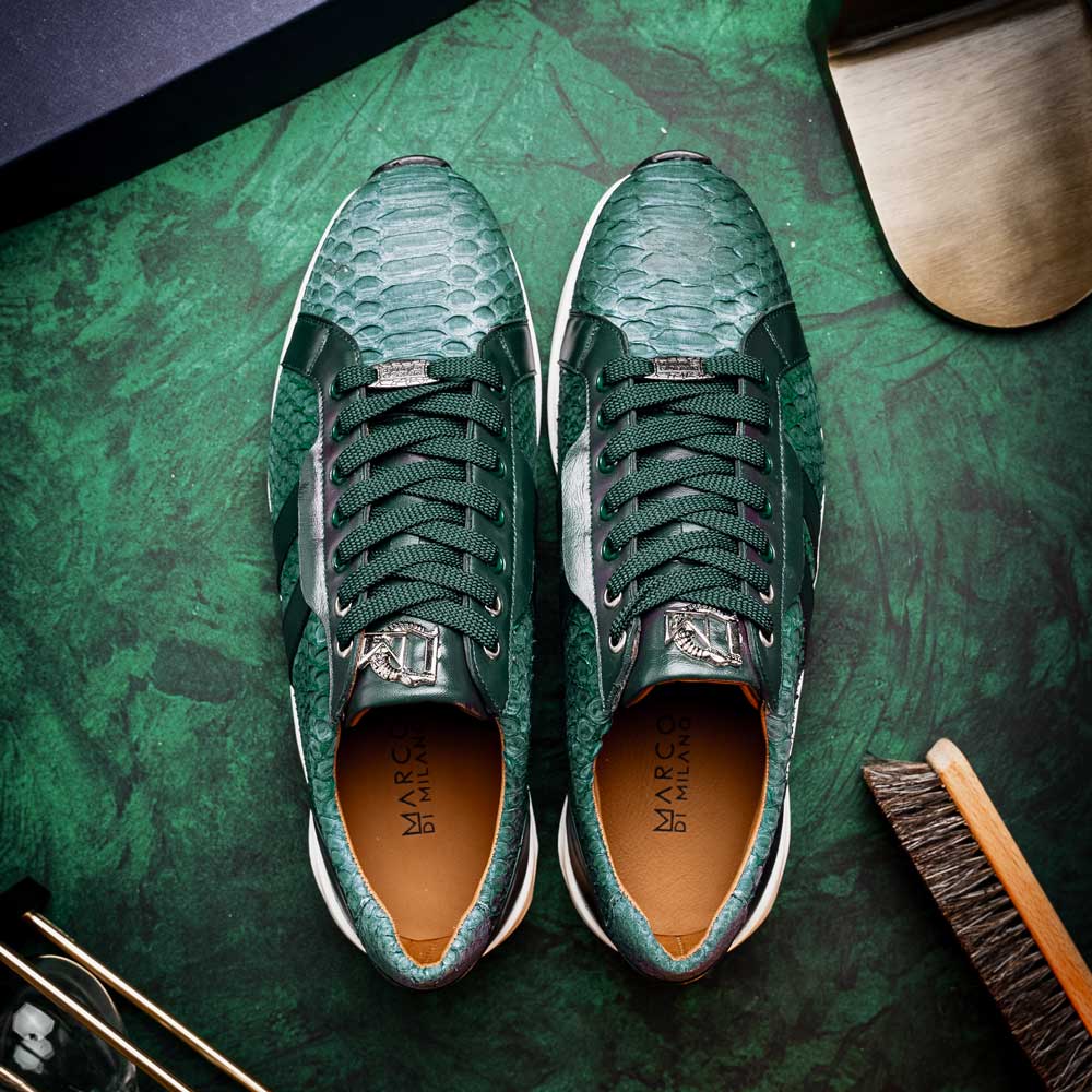 The Marco Di Milano Verona Green sneakers are luxury shoes with scale-like patterns, dark green accents, and white soles. One shoe is upright while the other lies on its side.