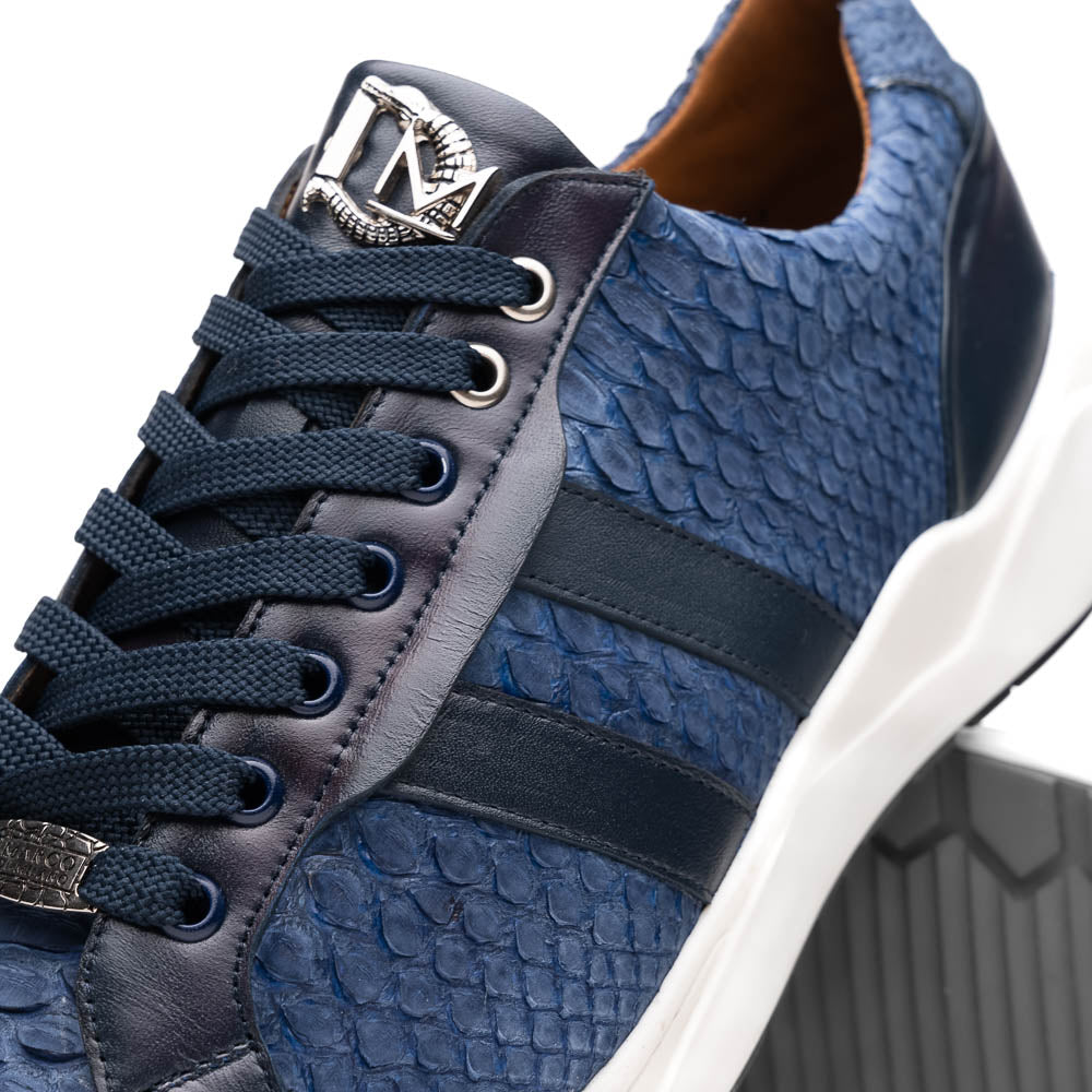 The Verona Navy sneakers by Marco Di Milano feature a blue python texture, navy laces, side stripes, and white rubber soles—luxury footwear with one shoe upright and the other on its side.