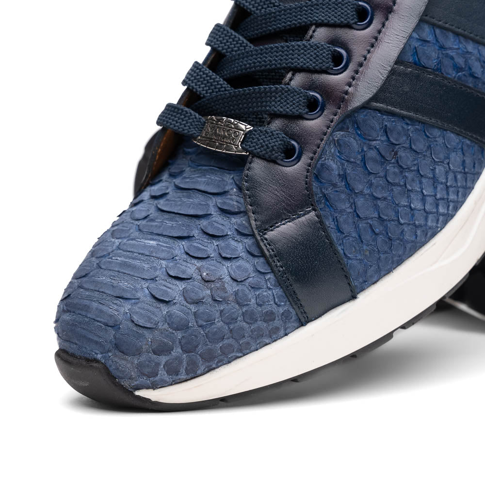 The Verona Navy sneakers by Marco Di Milano feature a blue python texture, navy laces, side stripes, and white rubber soles—luxury footwear with one shoe upright and the other on its side.