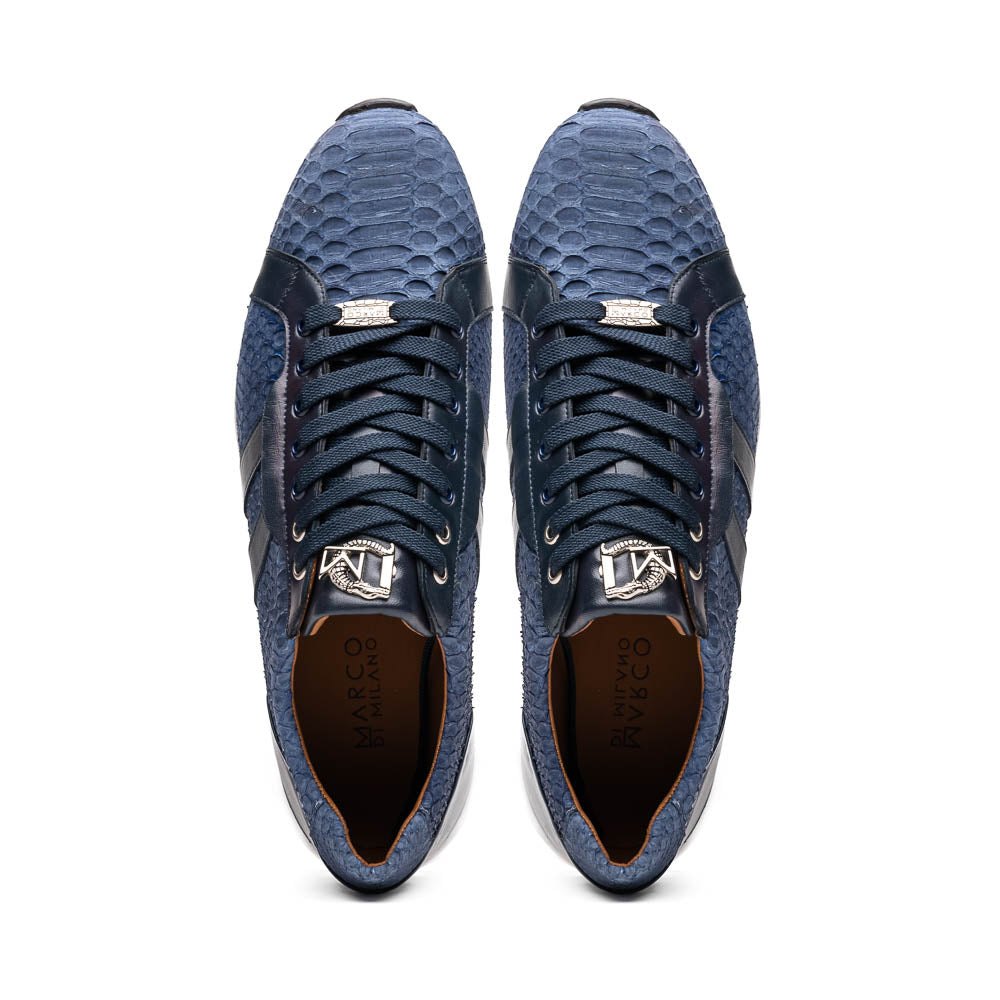 The Verona Navy sneakers by Marco Di Milano feature a blue python texture, navy laces, side stripes, and white rubber soles—luxury footwear with one shoe upright and the other on its side.