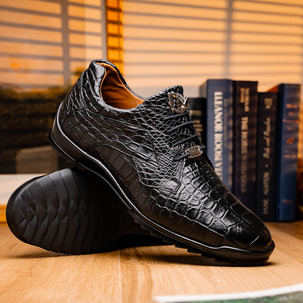 The Vulcan Black by Marco Di Milano are black, crocodile-patterned leather dress shoes with rubber soles—one upright and one displaying the sole. This luxury footwear features hand-painted finishes for a truly refined look.