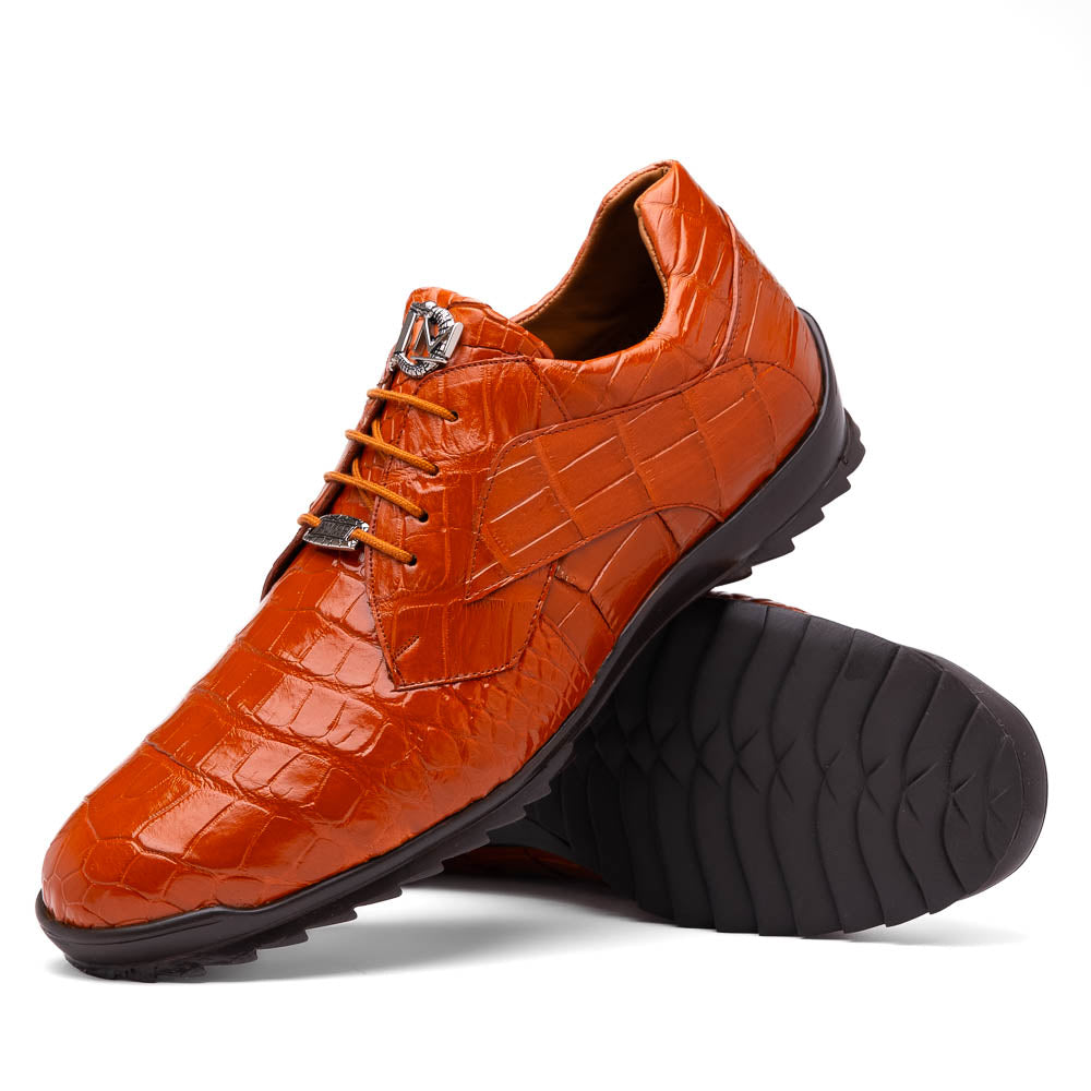The Marco Di Milano Vulcan Honey features orange, crocodile-patterned leather dress shoes with hand-painted finishes and black rubber soles; one shoe stands upright while the other rests on its side below.