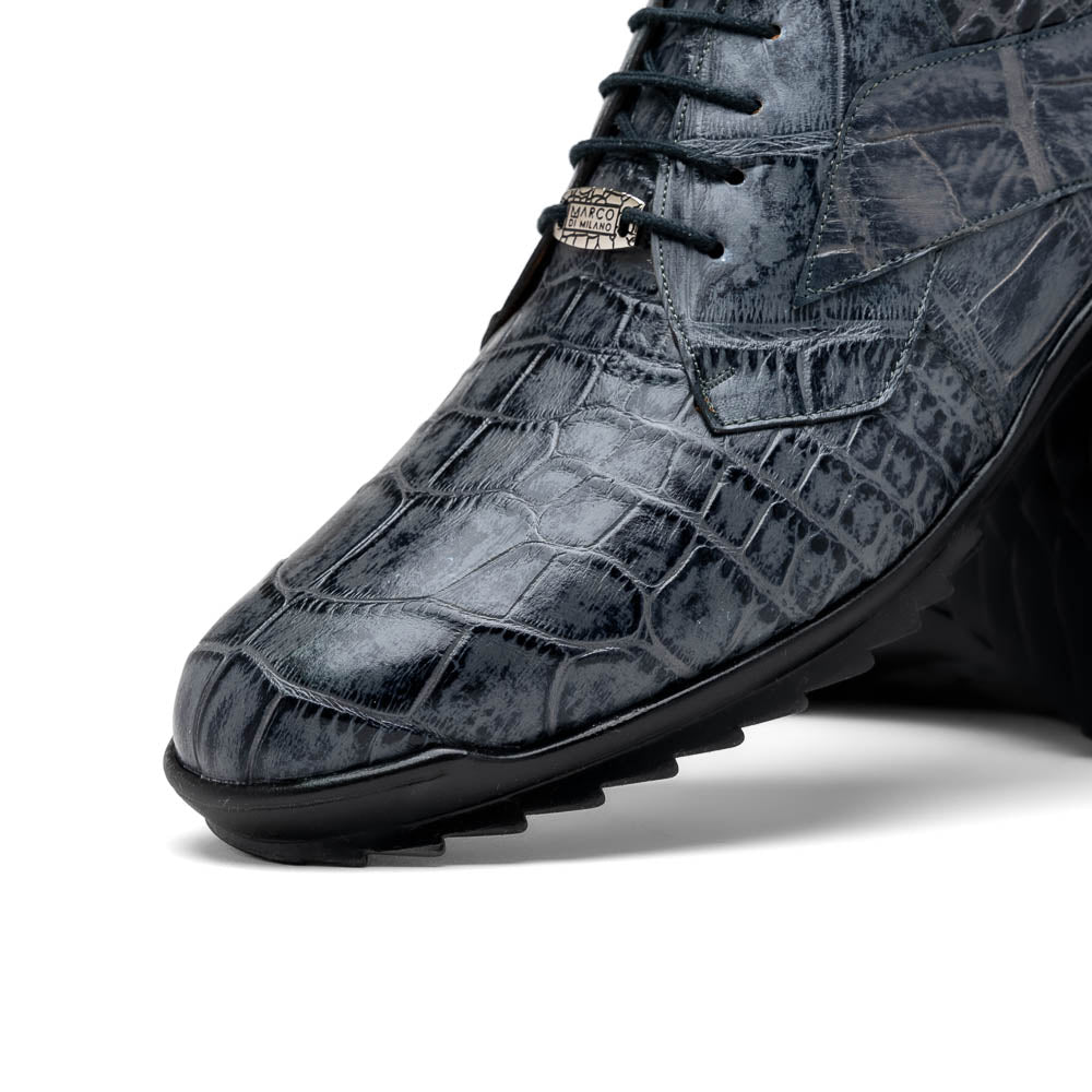 A pair of Marco Di Milano Vulcan Rustic Gray men's dress shoes, showcasing luxury footwear with crocodile-patterned leather, hand-painted finishes, and metal lace accents—one upright, one on its side to display the sole.