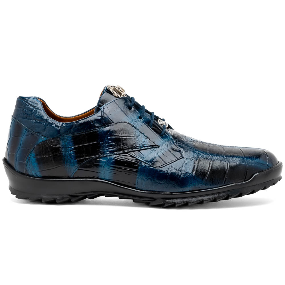 The Vulcan Rustic Navy by Marco Di Milano features glossy blue and black lace-up dress shoes with textured leather, rubber soles, and exquisite hand-painted finishes—one upright, the other propped beneath it—showcasing luxury footwear.