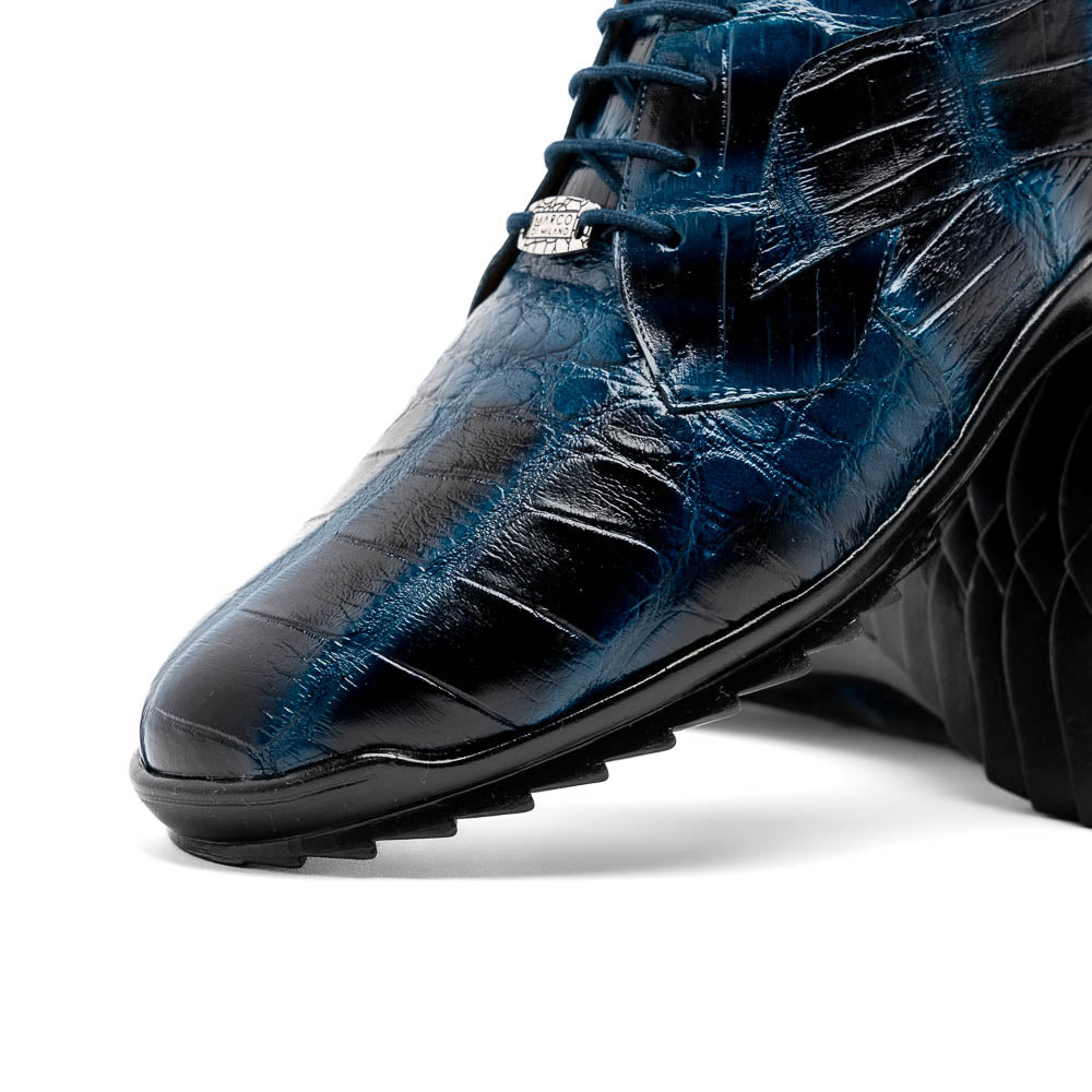 The Vulcan Rustic Navy by Marco Di Milano features glossy blue and black lace-up dress shoes with textured leather, rubber soles, and exquisite hand-painted finishes—one upright, the other propped beneath it—showcasing luxury footwear.