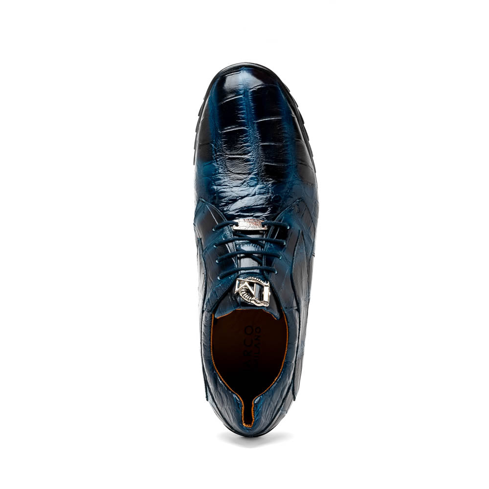 The Vulcan Rustic Navy by Marco Di Milano features glossy blue and black lace-up dress shoes with textured leather, rubber soles, and exquisite hand-painted finishes—one upright, the other propped beneath it—showcasing luxury footwear.