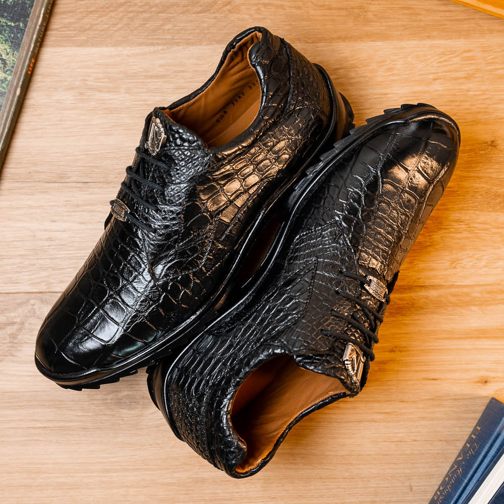 The Vulcan Black by Marco Di Milano are black, crocodile-patterned leather dress shoes with rubber soles—one upright and one displaying the sole. This luxury footwear features hand-painted finishes for a truly refined look.