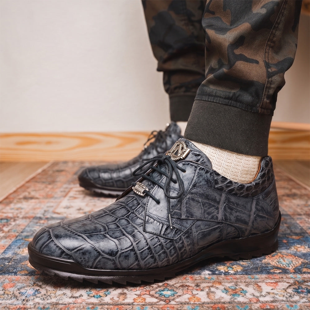 A pair of Marco Di Milano Vulcan Rustic Gray men's dress shoes, showcasing luxury footwear with crocodile-patterned leather, hand-painted finishes, and metal lace accents—one upright, one on its side to display the sole.