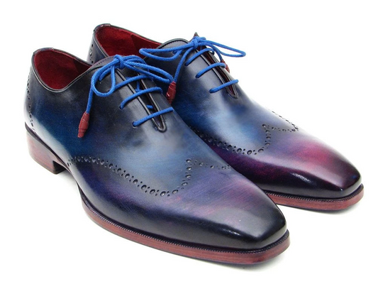 The Paul Parkman Blue & Purple Wingtip Oxfords - 084VX55 are a distinguished pair of men's dress shoes crafted from hand-painted leather with a captivating blue to purple gradient. Featuring blue laces and decorative perforations, these handmade brogues embody a unique blend of style and craftsmanship, making them an elegant choice for the discerning individual.