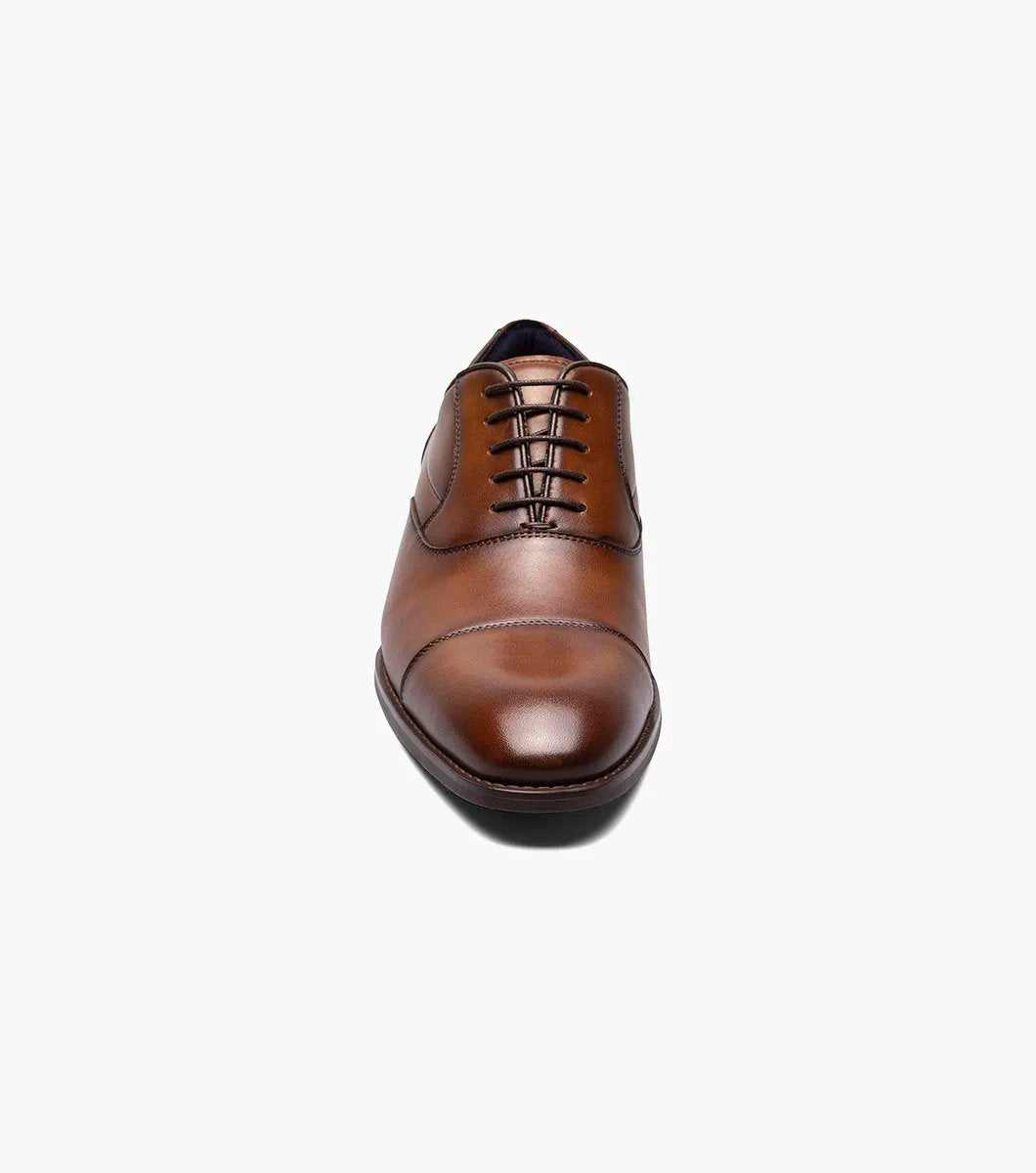 The STACY ADAMS Kallum Cap Toe Oxford in Cognac (25568-221) is a brown men's dress shoe with a cushioned footbed and dark laces, shown on a white background.