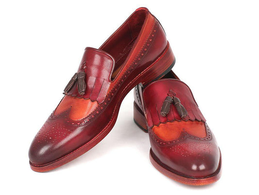 A pair of Paul Parkman Kiltie Tassel Loafers in Tobacco & Bordeaux, KT64CB, exquisitely crafted from handpainted calfskin with brown fringe details and intricate brogue patterns, arranged artfully with one shoe tilted against the other.