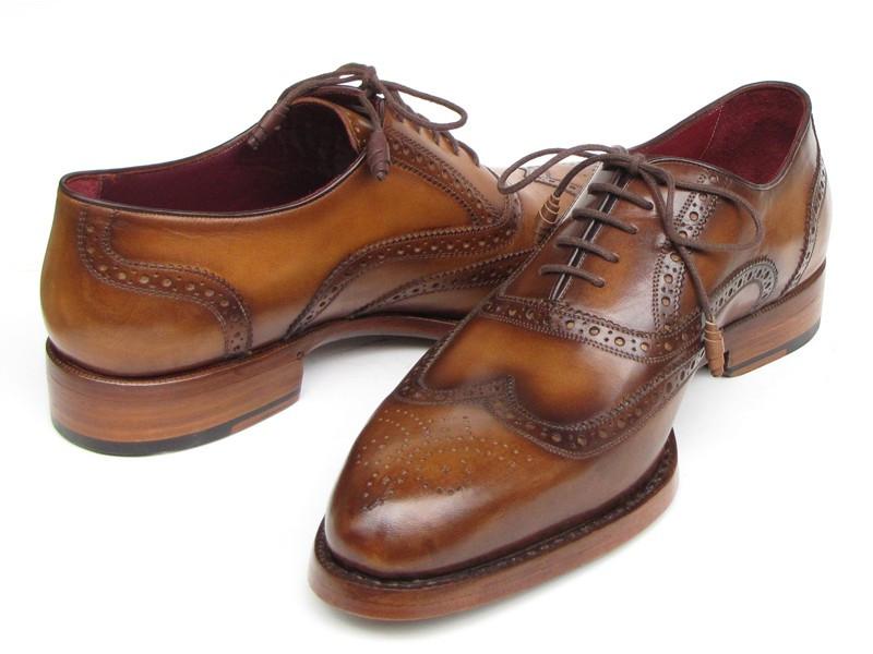 The Paul Parkman Wingtip Oxford Goodyear Welted Tobacco - 027-TAB shoes by Paul Parkman are exquisite handmade brown leather brogues that boast intricate designs and feature laces with Goodyear welted construction. Their elegant wooden soles enhance their appeal, beautifully displayed on a white background.