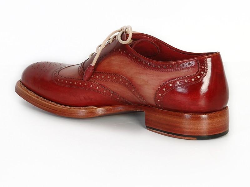 A pair of polished Bordeaux and camel leather Wingtip Oxfords with tan laces, featuring intricate perforations and visible stitching. These handmade shoes, named Paul Parkman Wingtip Oxfords Bordeaux & Camel - 027B, display the Paul Parkman brand name inside one shoe.