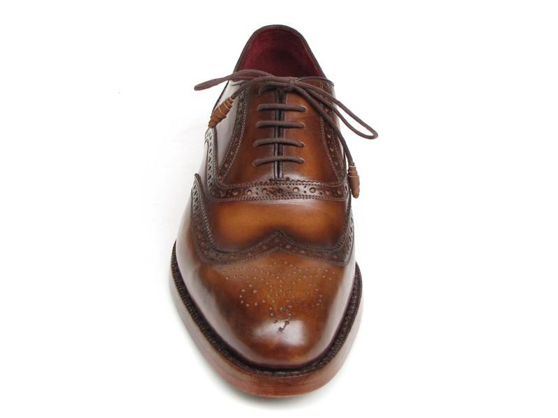 The Paul Parkman Wingtip Oxford Goodyear Welted Tobacco - 027-TAB shoes by Paul Parkman are exquisite handmade brown leather brogues that boast intricate designs and feature laces with Goodyear welted construction. Their elegant wooden soles enhance their appeal, beautifully displayed on a white background.