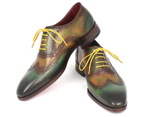 A pair of Paul Parkman Wingtip Oxfords Green Handpainted Calfskin - 228-GRN, adorned with yellow laces, is elegantly displayed with one shoe leaning on the other.