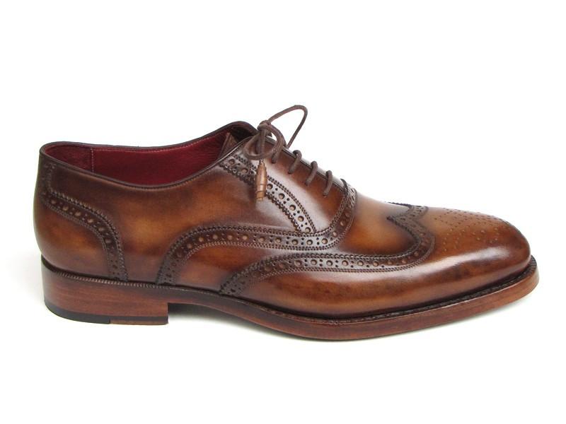 The Paul Parkman Wingtip Oxford Goodyear Welted Tobacco - 027-TAB shoes by Paul Parkman are exquisite handmade brown leather brogues that boast intricate designs and feature laces with Goodyear welted construction. Their elegant wooden soles enhance their appeal, beautifully displayed on a white background.