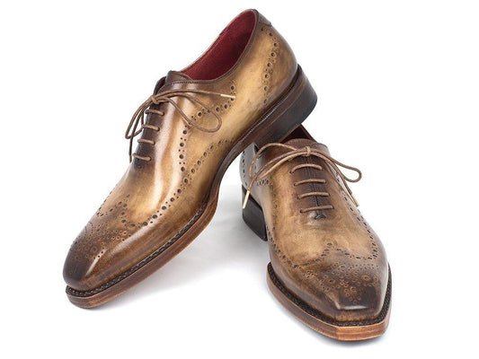 A pair of Paul Parkman Goodyear Welted Wingtip Oxfords in Antique Olive, featuring decorative perforations, laces, and a wooden sole, is displayed on a white background.