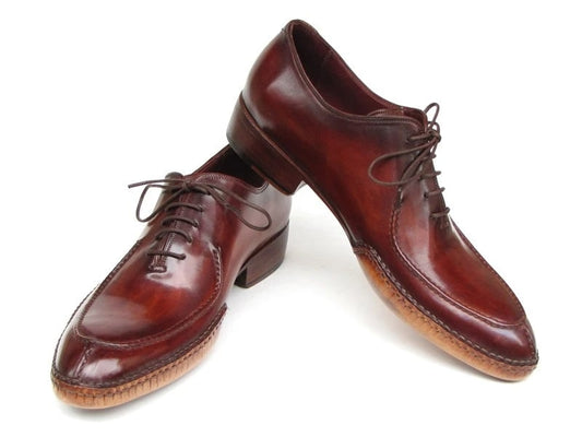 A pair of Paul Parkman Side Handsewn Split-toe Burgundy Oxfords (054-BUR), designed as men's oxfords with laces, featuring a raised heel and stitched details on the soles.