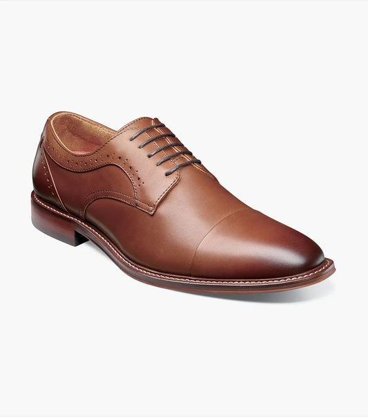 The Stacy Adams Maddox Cap Toe Oxford in chocolate features a leather upper with laces and subtle decorative stitching. This men's dress shoe is shown on a white background.