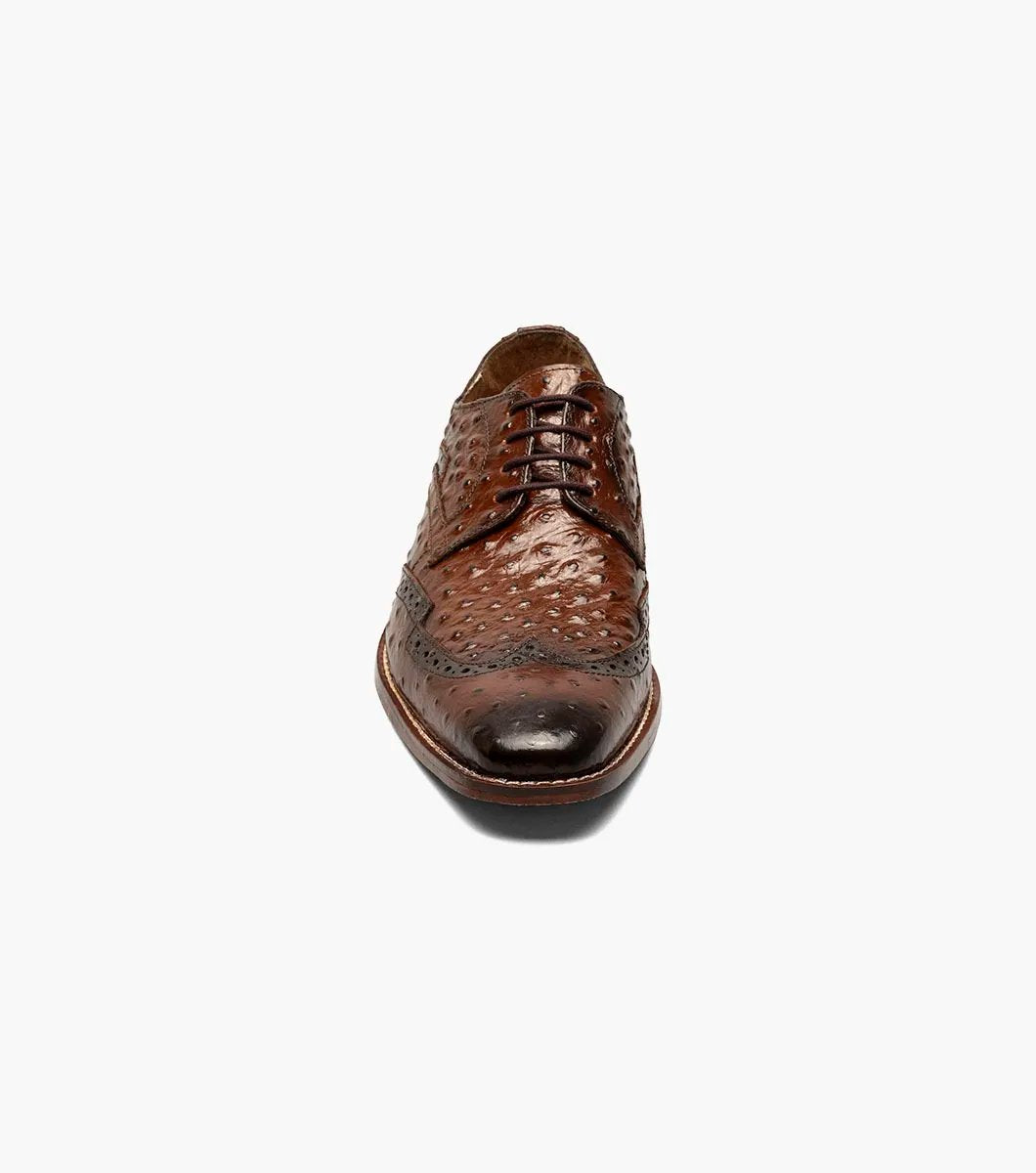 The Stacy Adams GENNARO Wingtip Oxford in cognac showcases a brown ostrich quill print leather design with intricate brogue detailing and a lace-up closure, complemented by anatomical arch support, offering an elegant side view.